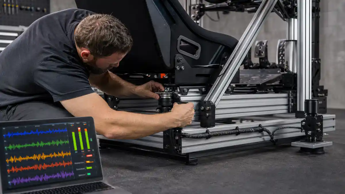 Technician mounts a tactile transducer beneath a telemetry-enabled racing cockpit